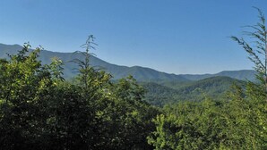 A mountainous landscape with dense greenery and clear blue skies. - Highpoint Escape by Jackson Mountain Rentals (Gatlinburg)