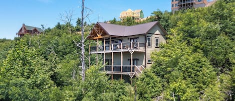 Ein mehrstöckiges Gebäude mit einem Balkon im zweiten Stock, umgeben von üppiger Vegetation.