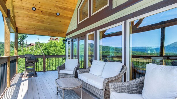 A covered outdoor deck with wicker furniture and a grill.