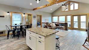 A spacious kitchen with a granite countertop, wooden beams, and a dining area with chairs and a table.
