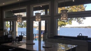 A kitchen with a large island, large windows with a view of a lake, and pendant lighting. - Beautiful gated lakefront home built im 2020 (Mabank)