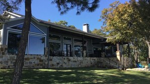 A house with a stone exterior, large windows, and a covered porch. - Beautiful gated lakefront home built im 2020 (Mabank)
