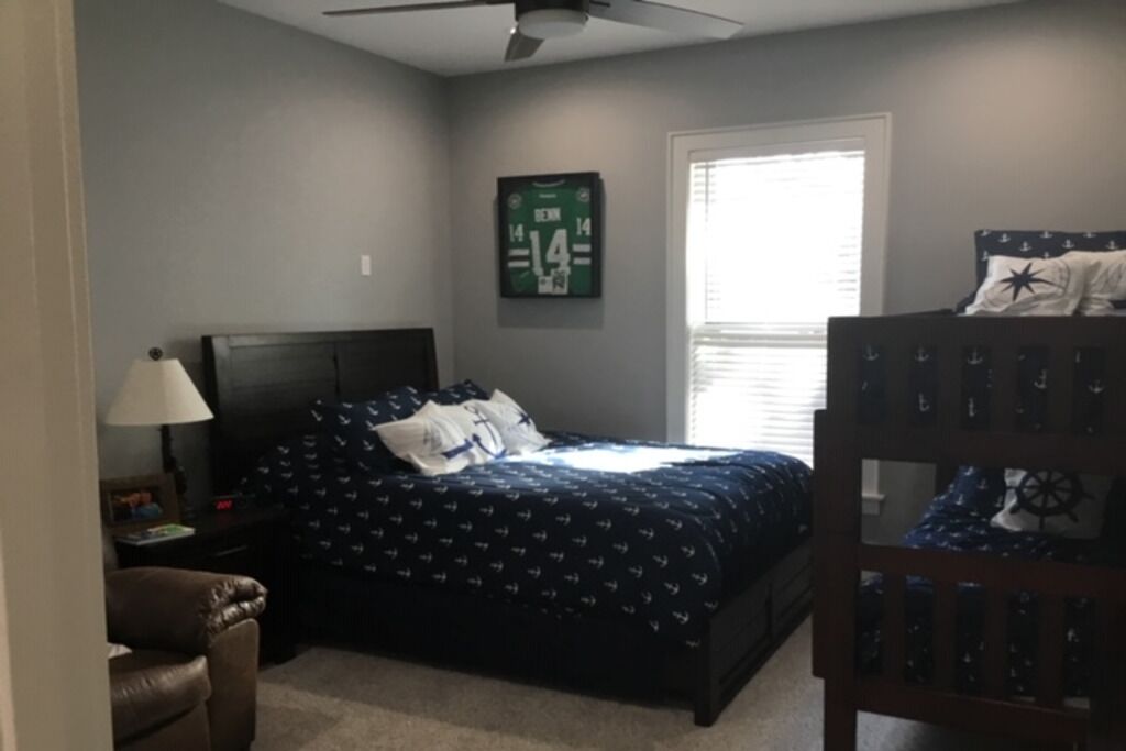 A bedroom with a bed, a chair, a desk, and a window.