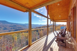 Une terrasse en bois offrant une vue sur les montagnes et les couleurs automnales.