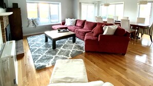 Ein geräumiges Wohnzimmer mit einem großen, roten Ecksofa, einem Couchtisch und einem Kamin.