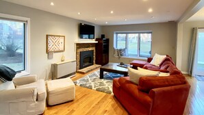 Ein modernes Wohnzimmer mit Kamin, einem roten Sofa, einem weißen Sessel und einem Couchtisch.
