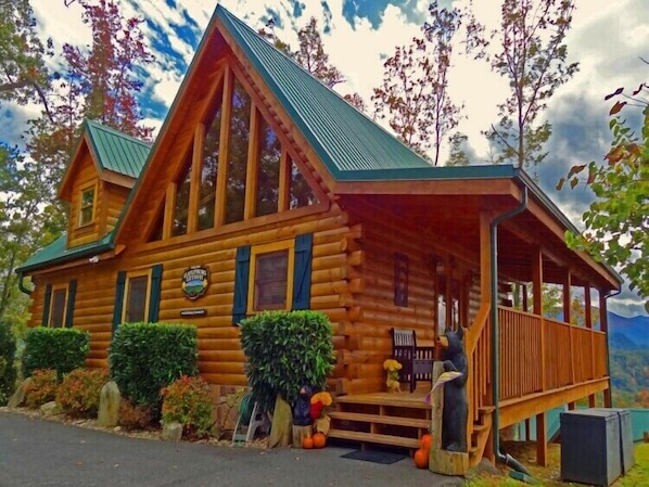 A log cabin with a porch, a chimney, and a sign indicating it is a lodge.