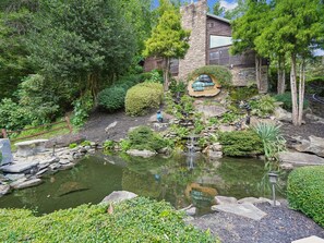 A pond with a waterfall, surrounded by lush greenery and a stone building with a sign that reads 'Black Bear Falls'. - Gatlinburg Getaway by Jackson Mountain Rentals (Gatlinburg)