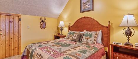A bedroom with a wooden bed, a ceiling fan, a wooden wardrobe, and a painting on the wall.