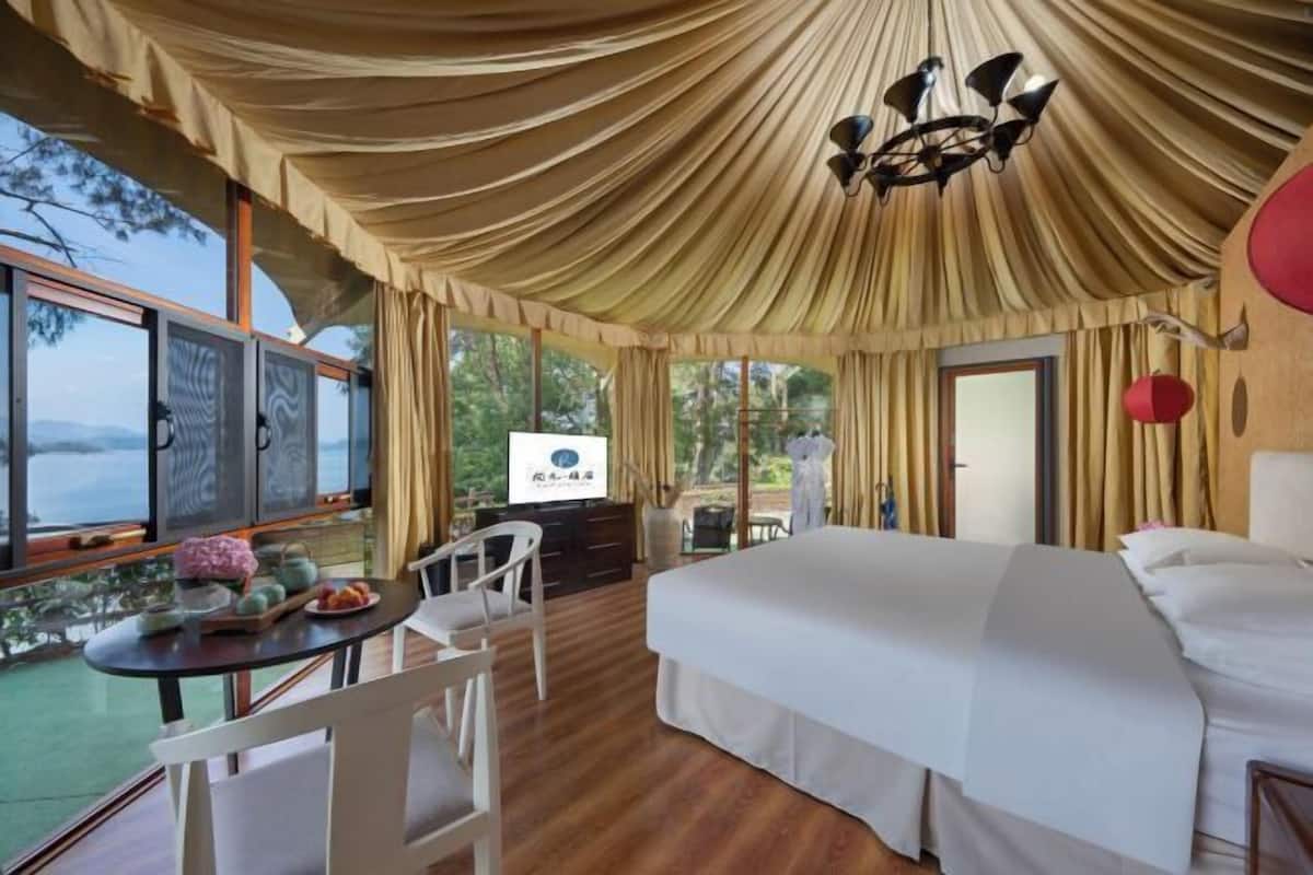 Ein geräumiges Schlafzimmer mit einem großen Bett, einem Esstisch mit Stühlen und Blick ins Freie.