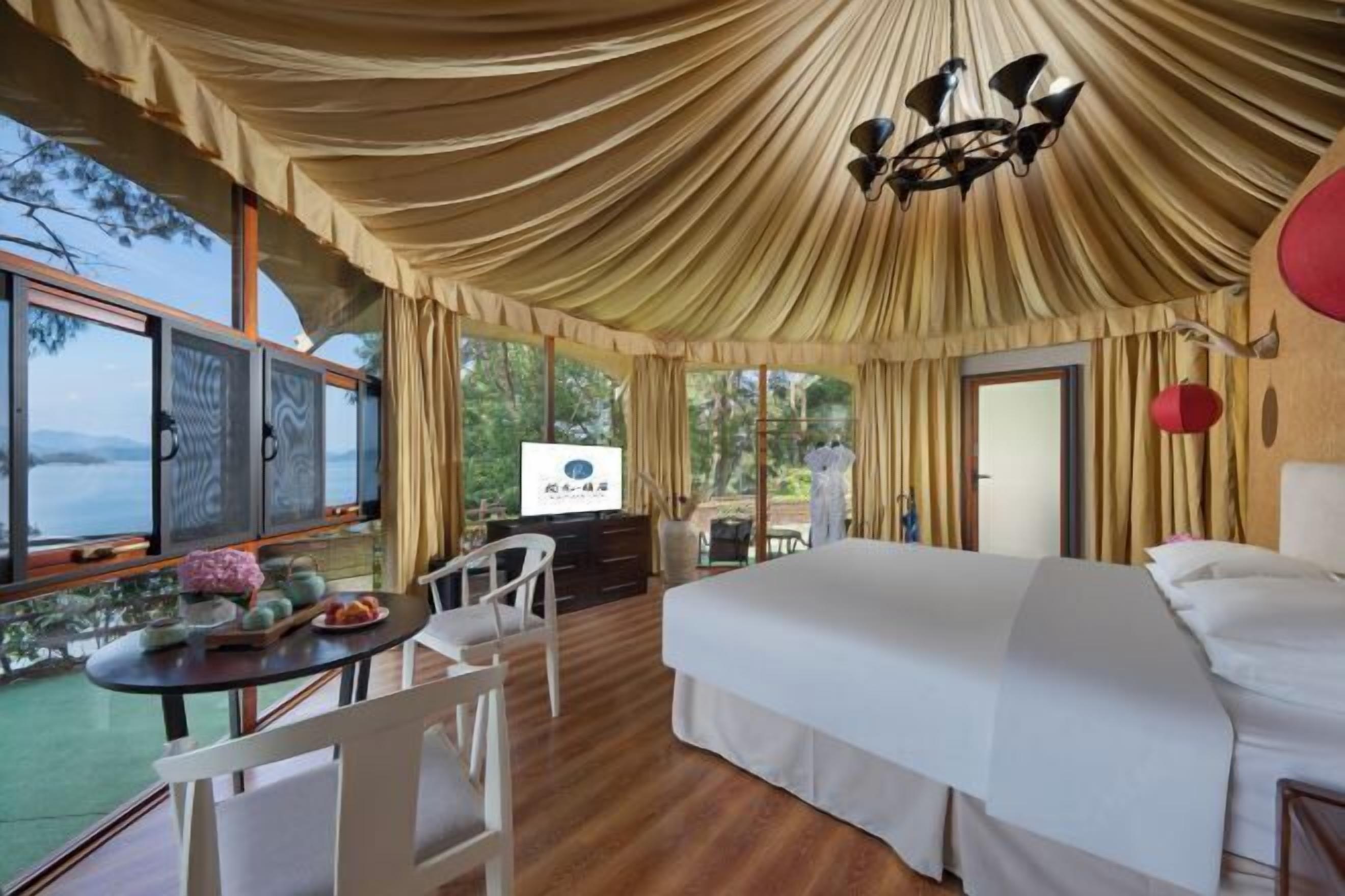A spacious bedroom with a large bed, a dining table with chairs, and a view of the outdoors.