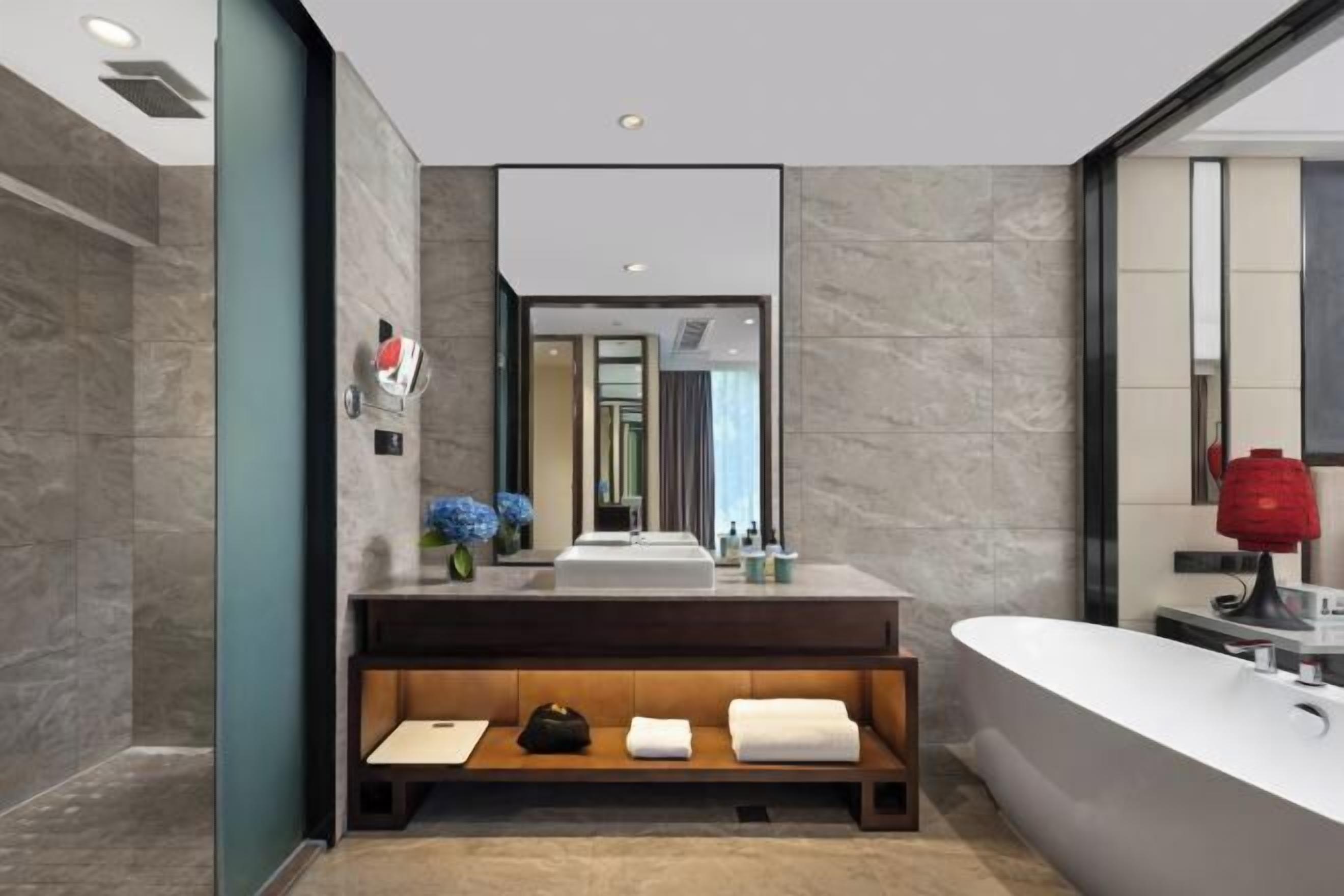 A modern bathroom with a large mirror, a freestanding bathtub, and a vanity with a sink.