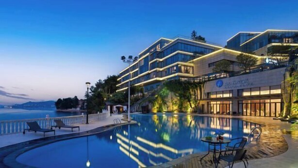 A modern hotel with a pool, outdoor seating, and a view of the sea. - Qiandaohu Kaiyuan Life Hotel (Chun'an)