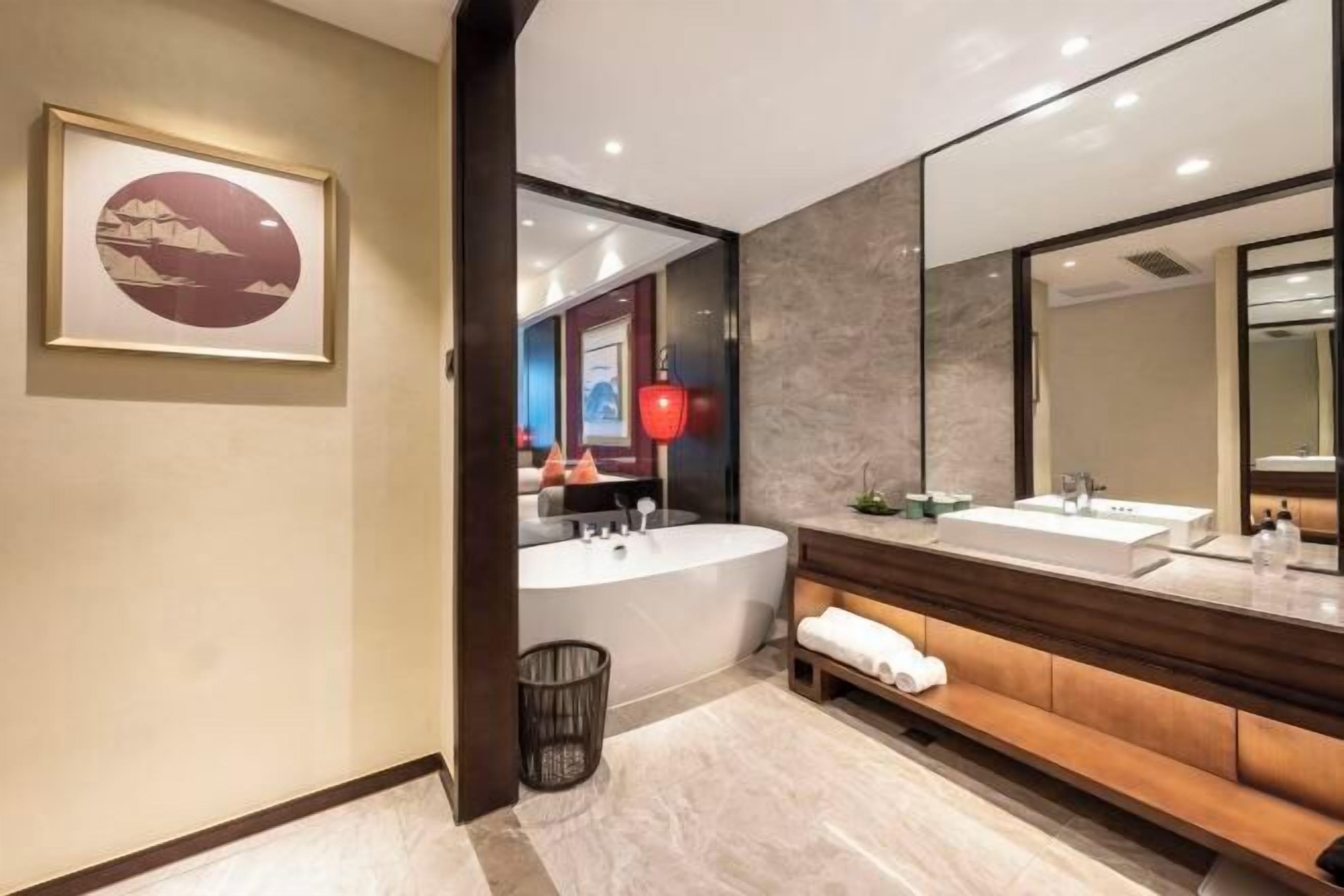 Ein modernes Badezimmer mit einer großen Badewanne, einem Waschtisch mit Spiegel und einem gerahmten Bild an der Wand.