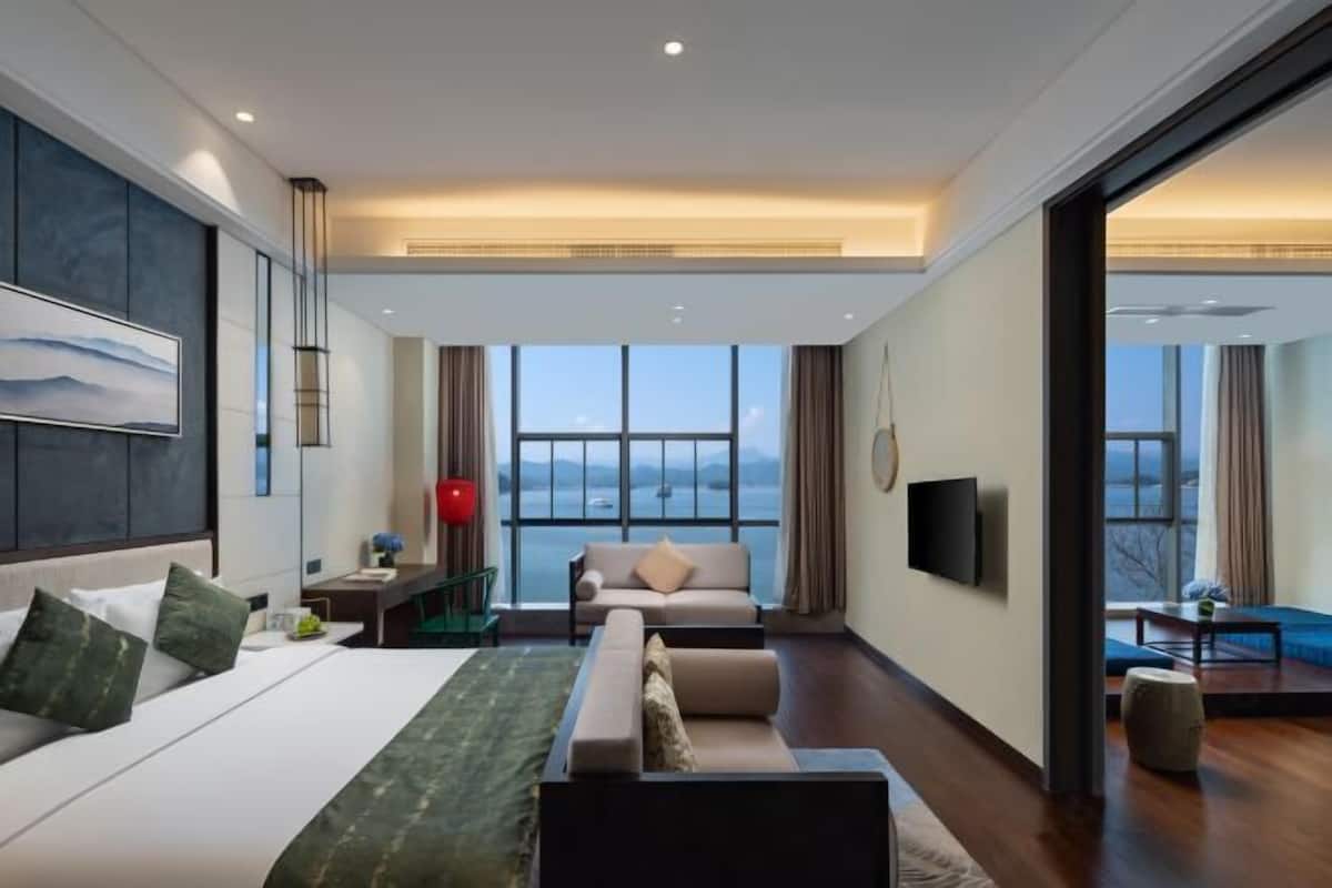 Ein modernes Hotelzimmer mit einem großen Bett, einer Couch, einem Fernseher und Meerblick.