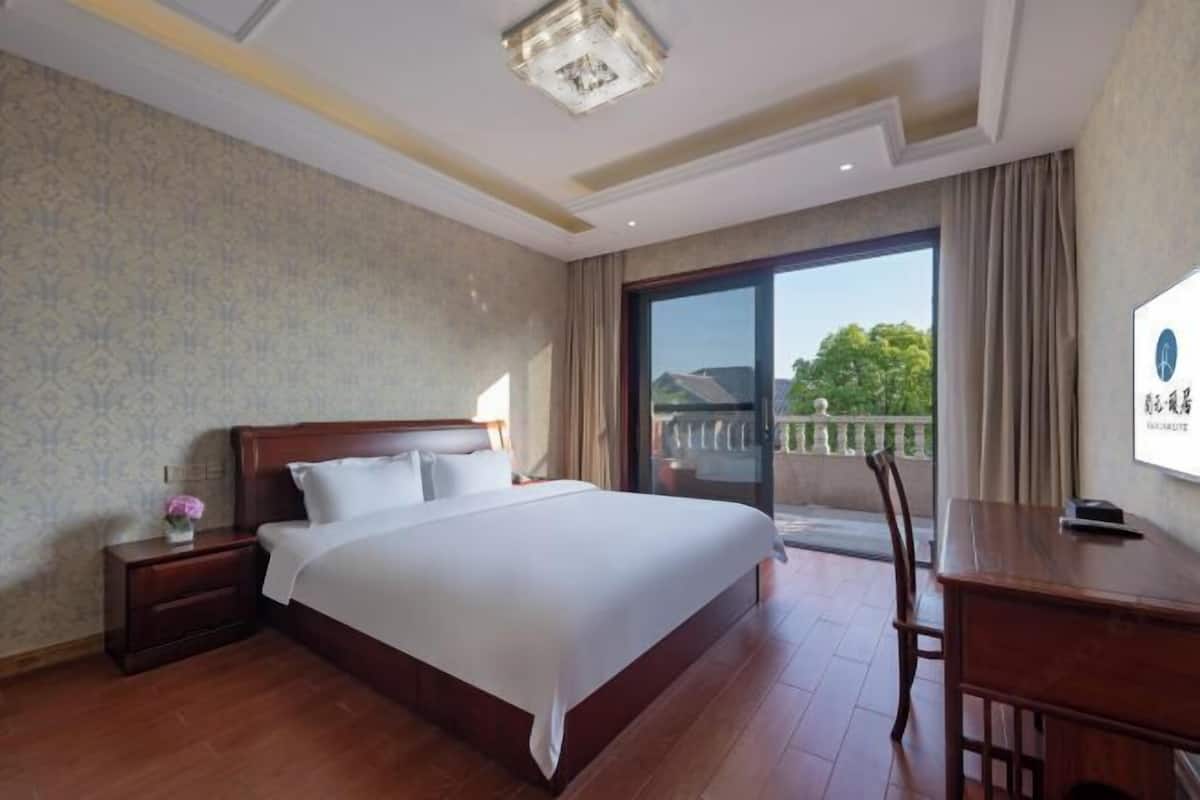 Ein Hotelzimmer mit einem großen Bett, einem Schreibtisch und Blick ins Freie durch eine Schiebetür.