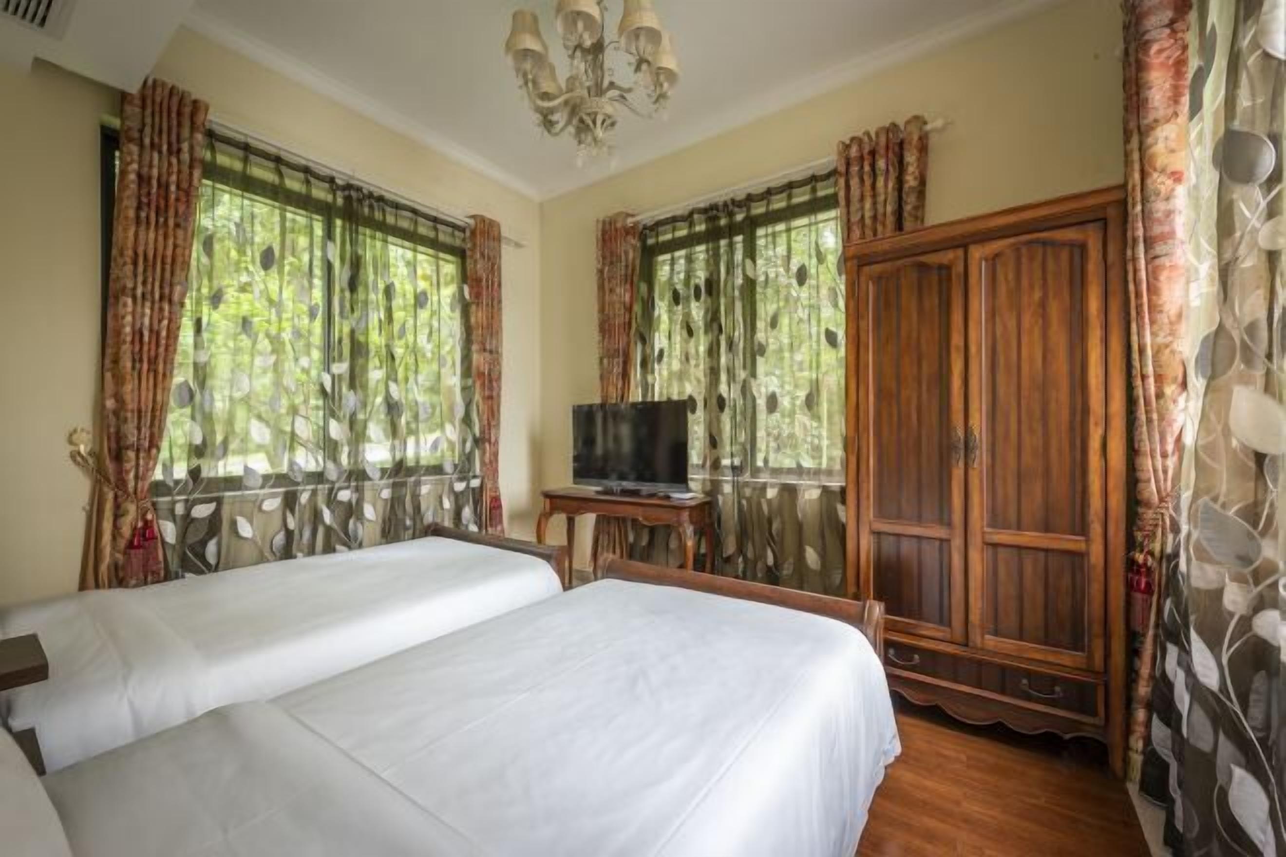 Una habitación de hotel con dos camas, un televisor sobre una mesita y un armario grande.