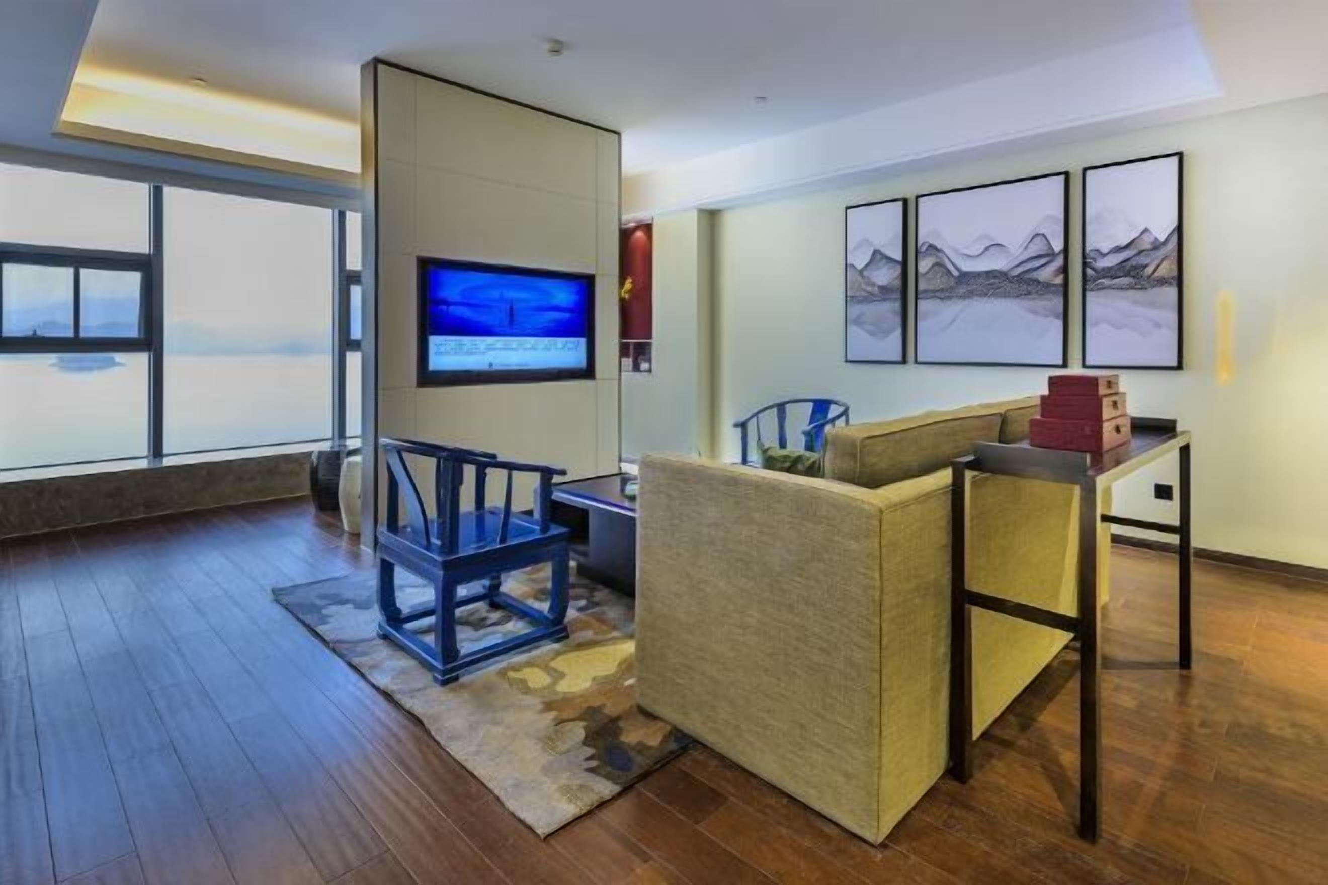 A modern living room with a large window, a flat-screen TV, a sofa, a coffee table, and framed artwork on the wall.