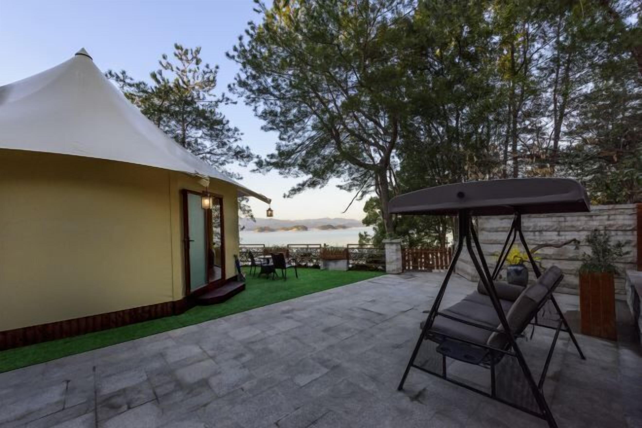 Alojamiento con tienda de campaña, zona de patio, mobiliario exterior y vista al mar.