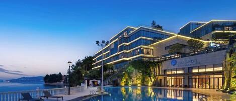 A hotel with a pool, a dining area, and a view of the sea.