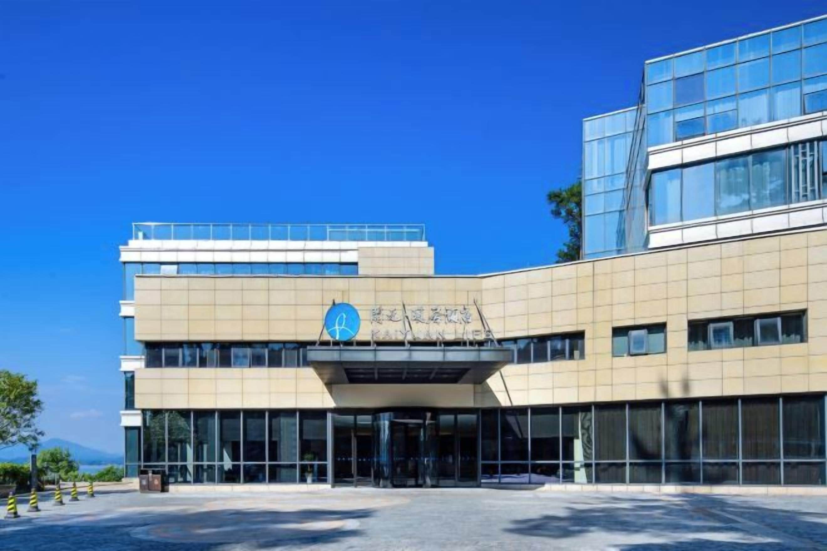 A modern building with a prominent entrance, large windows, and a clear sky.