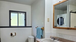 Un baño con inodoro, lavamanos, ventana y espejo.