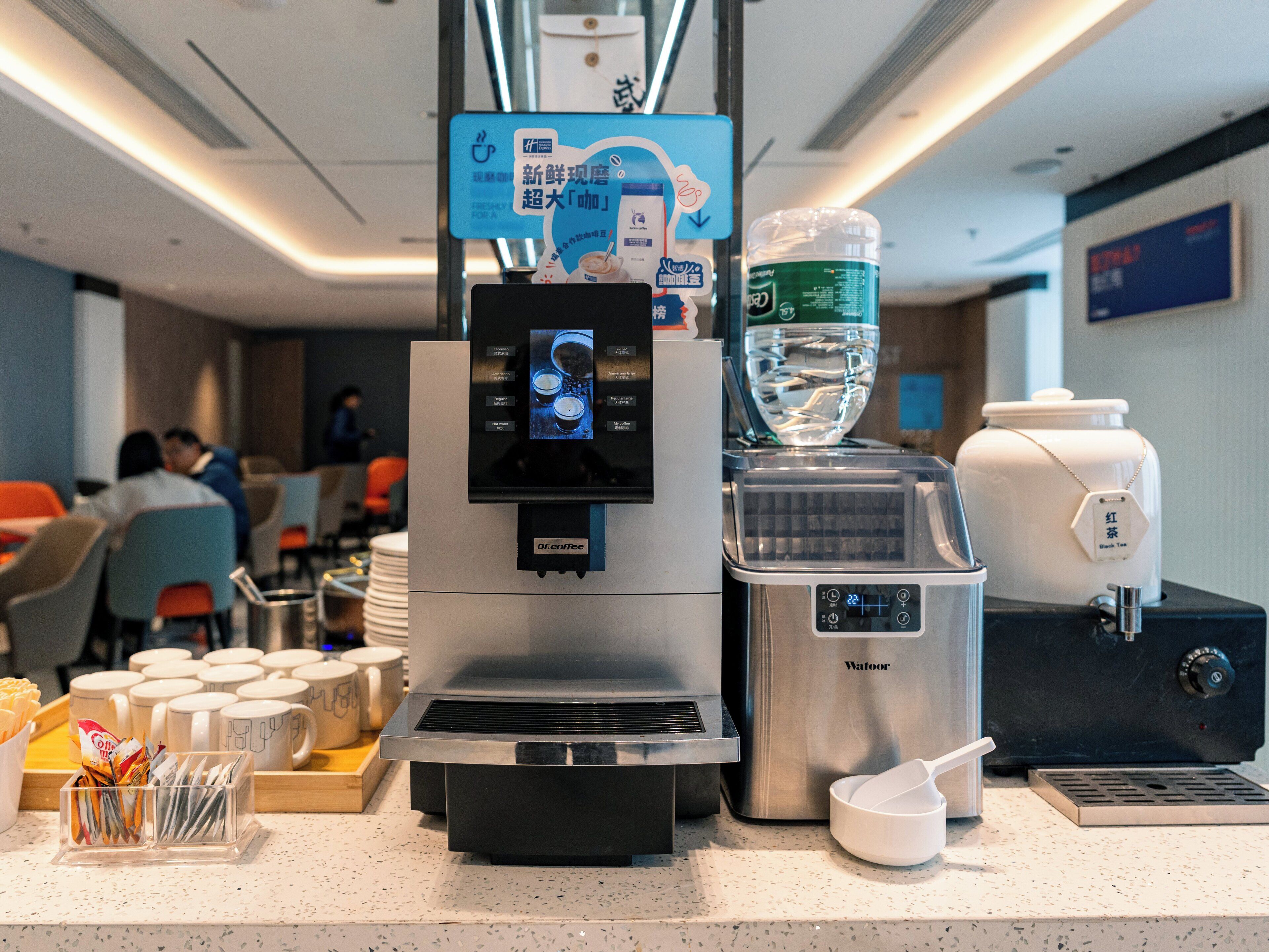 A coffee machine with a digital display, a water dispenser, and a tea dispenser on a counter.