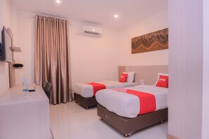 Habitació d'hotel amb dos llits, una escriptori, una cadira, aire condicionat i un quadre a la paret.