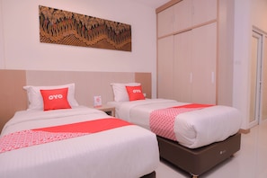 Ein Hotelzimmer mit zwei Betten, jeweils mit weißer und roter Bettdecke, und einem großen Kunstwerk darüber.