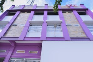 Un immeuble à plusieurs étages, doté d’une façade violette, de grandes fenêtres et d’une enseigne bien visible avec les lettres « OYO ».