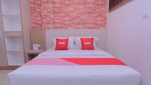Hotelkamer met een bed, twee kussens met 'OYO'-logo, een rood-witte plaid en een muur met een baksteenmotief.