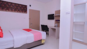 Een hotelkamer met een bed, een bureau, een televisie en een kledingkast.