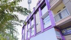Een meerhoog gebouw met een paarse gevel, een zichtbaar bord voor een babywinkel, en een helder uitzicht op de lucht.