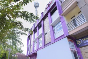 Un immeuble à plusieurs étages, doté d’une façade violette, d’une enseigne bien visible indiquant qu’il s’agit d’un magasin de produits pour bébés, et offrant une vue dégagée sur le ciel.