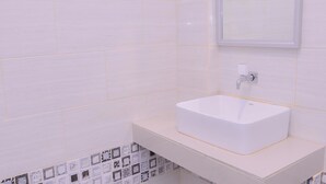 Une salle de bain avec un lavabo blanc, un miroir et des murs carrelés.