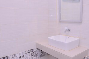 Une salle de bain avec un lavabo blanc, un miroir et des murs carrelés.