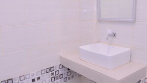 Een badkamer met een wit wastafel, een spiegel en betegelde muren.