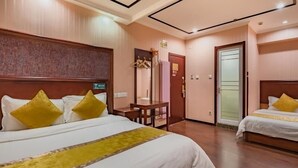 A hotel room with two beds, each with a wooden headboard and yellow pillows. There is a small table and a chair in the corner, and a door leading to another room. - Greentree Inn Beijing Yuegezhuang Hotel (Beijing)