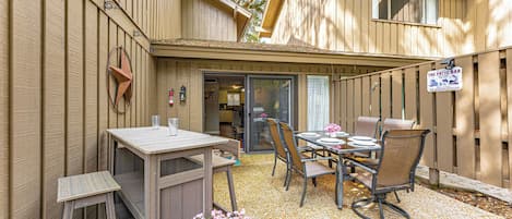 A patio area with a table and chairs, a wooden fence, and a sign for 'The Patio Bar'.