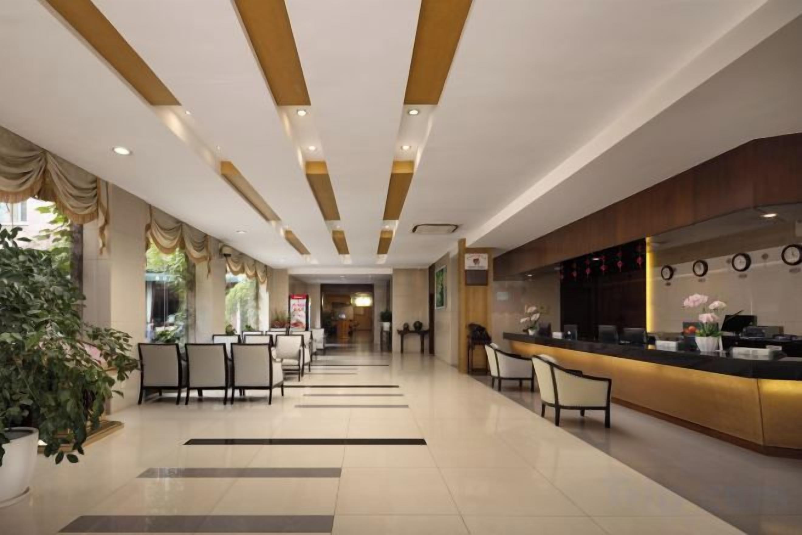 A hotel lobby with a reception desk, seating area, and a large potted plant.