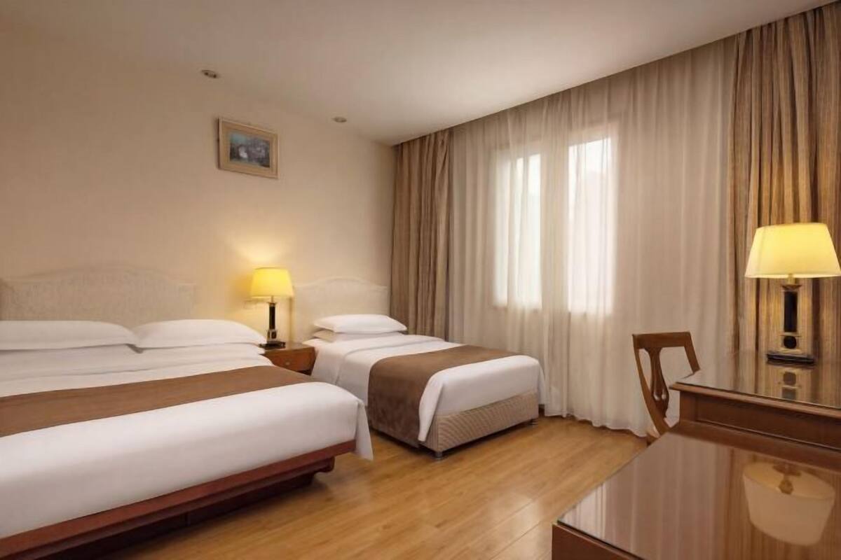 A hotel room with two beds, a desk, and a chair.