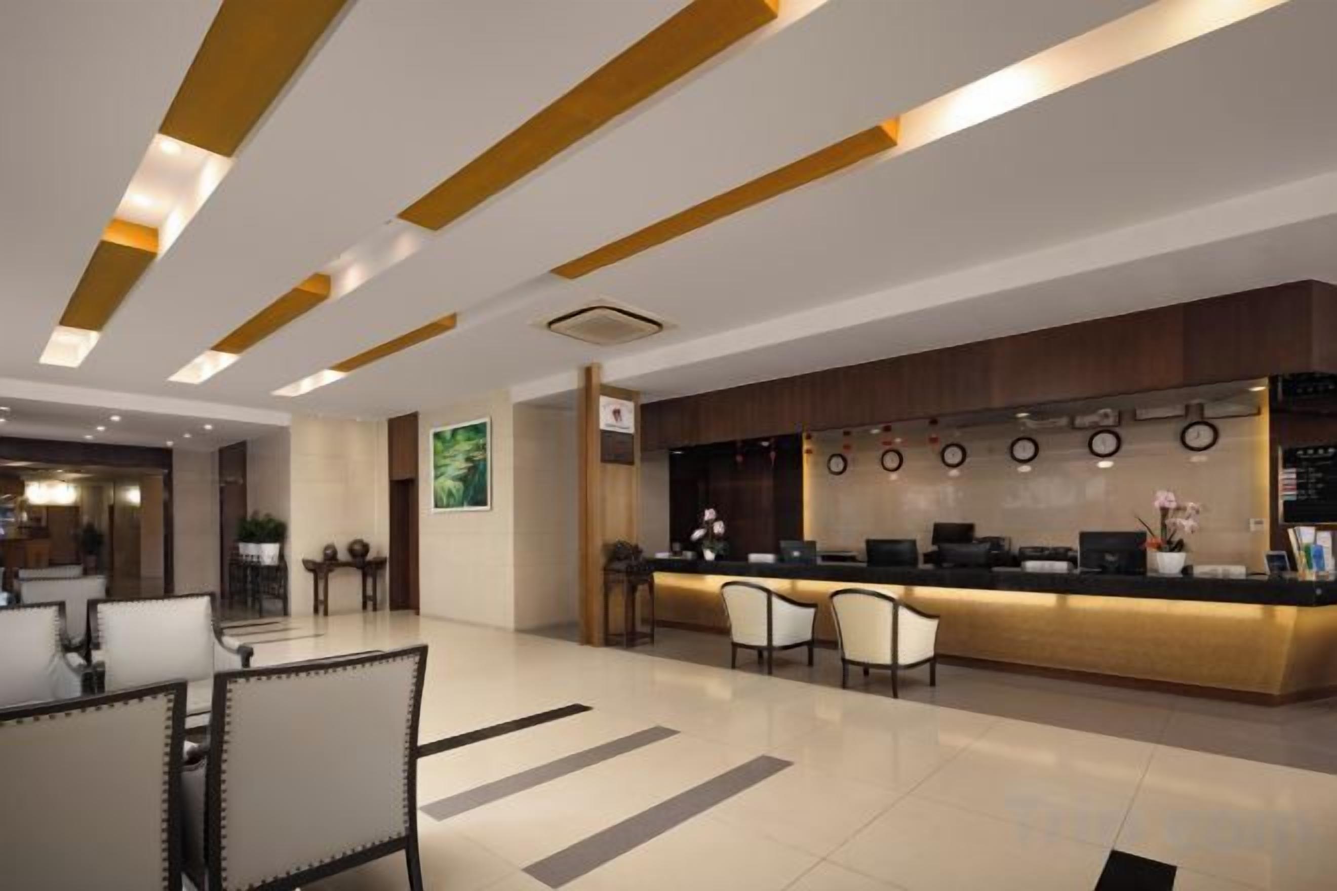 A modern hotel lobby with a reception desk, seating area, and a bar.