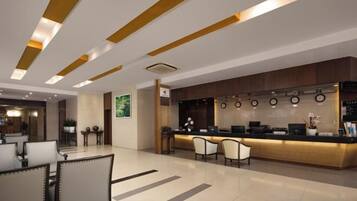 A modern hotel lobby with a reception desk, seating area, and a bar.