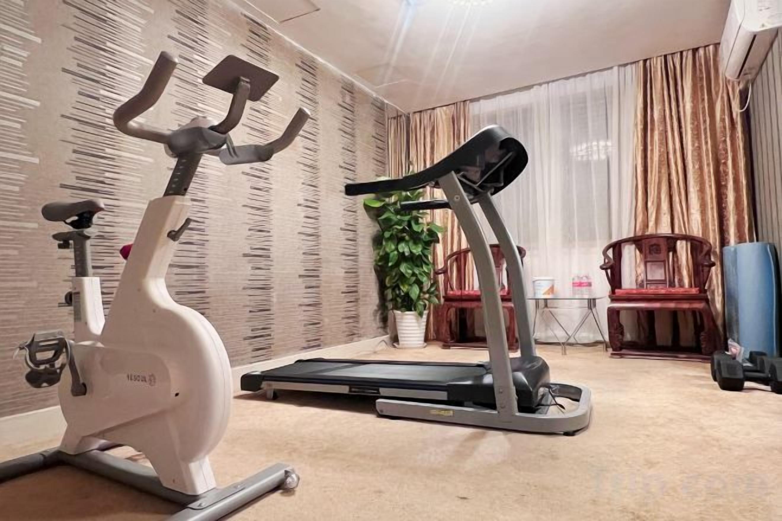 A home gym with an exercise bike, elliptical, and treadmill.