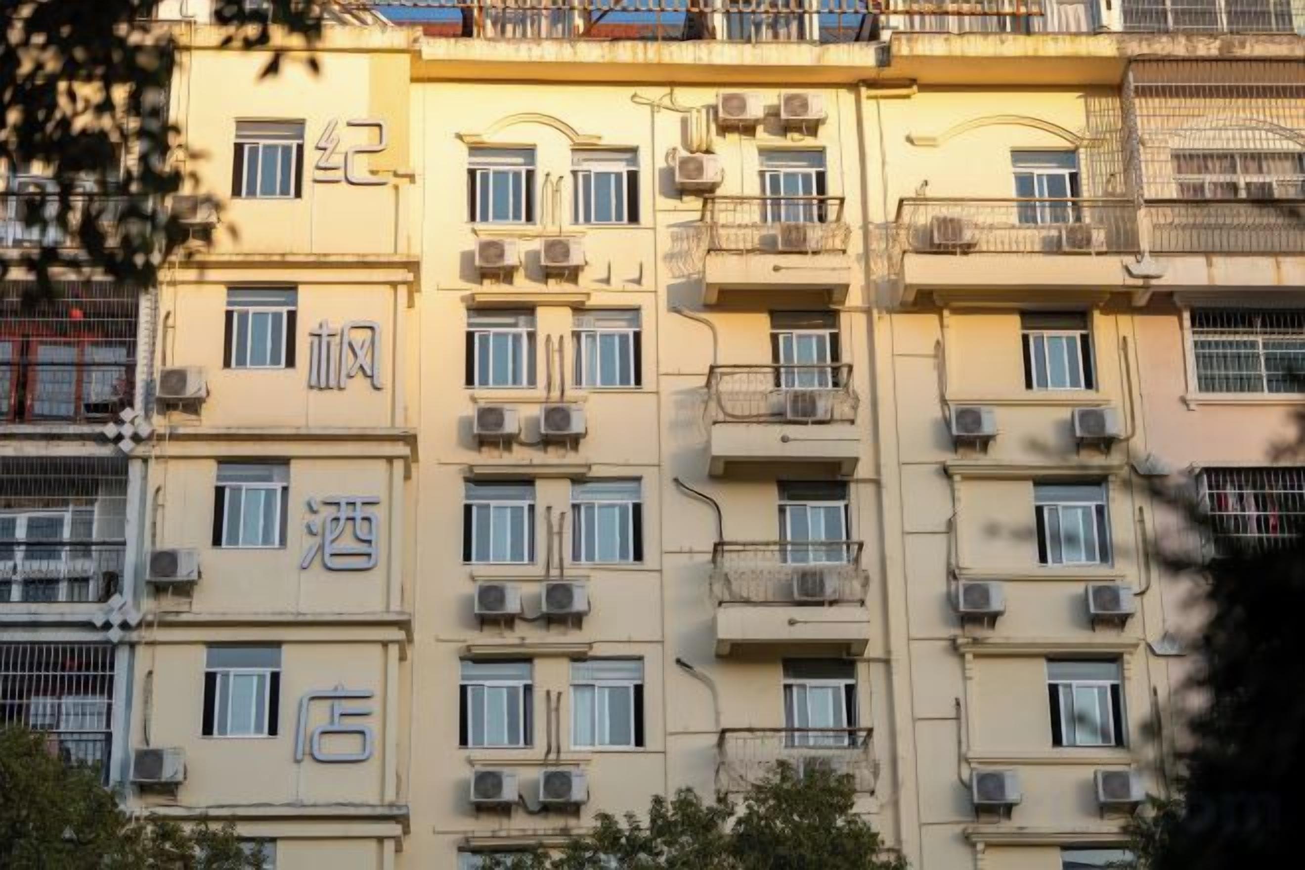 A multi-story building with balconies, air conditioning units, and signage indicating hotel and store facilities.