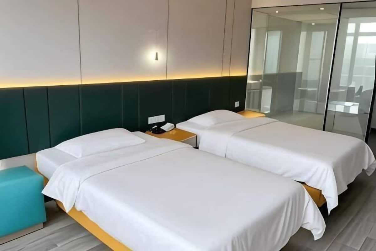 A hotel room with two beds, a nightstand, a mirror, and a view of the room's interior.