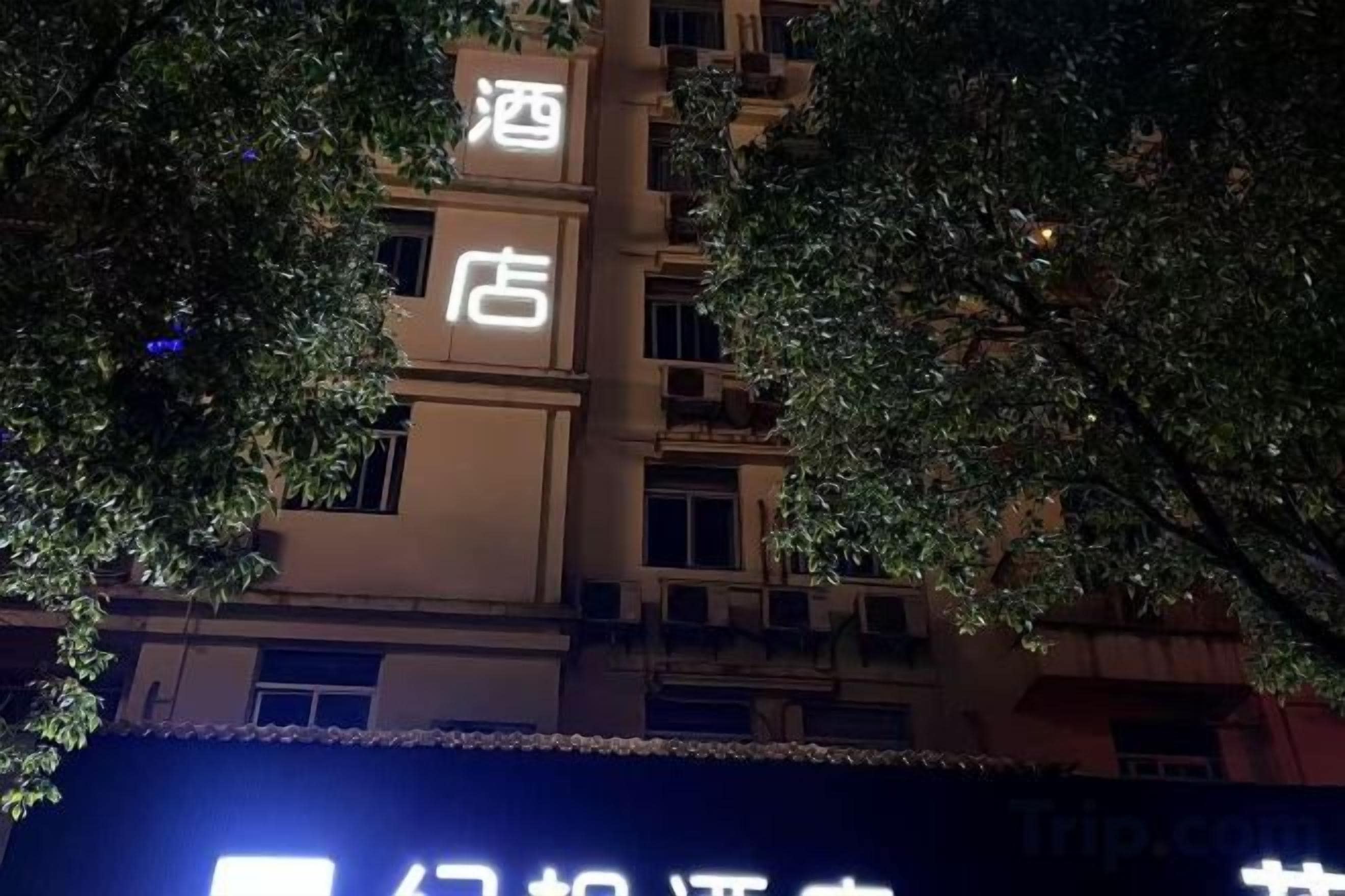A hotel sign with the name '酒店' and a website address 'Trip.com'.