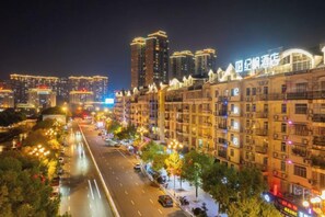 A nighttime cityscape with illuminated buildings and a busy street. - JiFeng Hotel (Dehua Cidu Avenue) (Quanzhou)