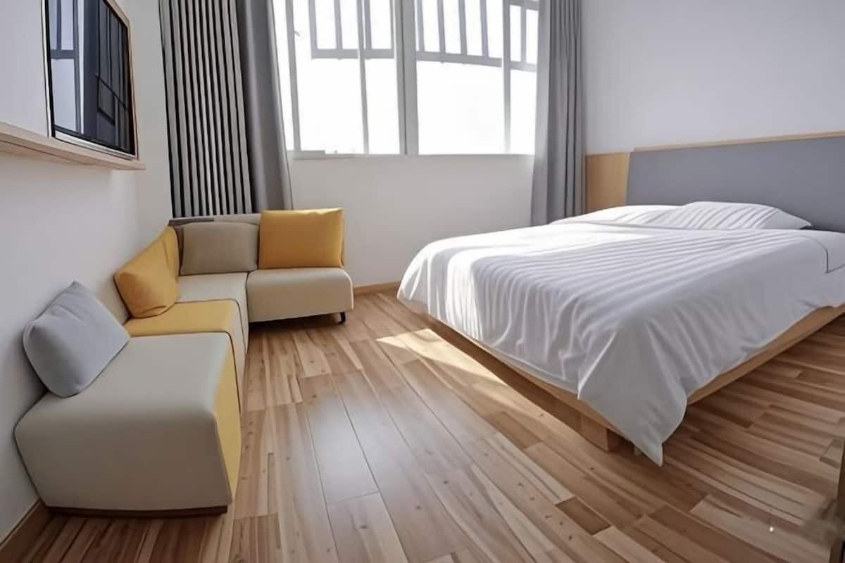 A modern bedroom with a bed, a sofa, and a window.