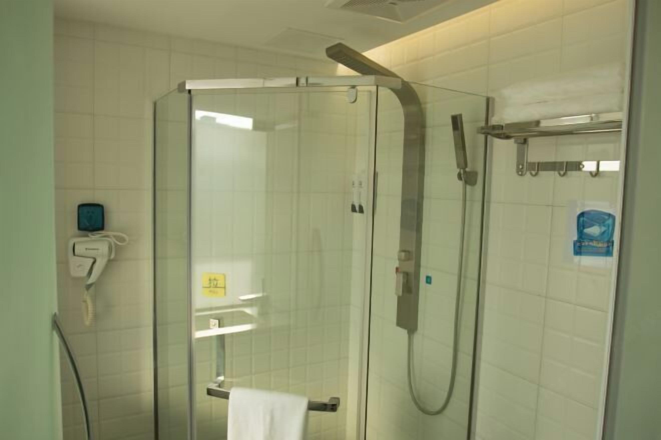 A glass-enclosed shower stall with a handheld showerhead and a towel rack.